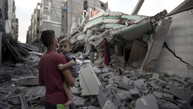 Foto van man met kind die naar kapot geschoten en gebombardeerde huizen kijkt