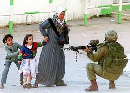 Foto: Twee kinderen verschuilen zich achter moeder tegenover een Israelische militair met geweer in aanslag 
