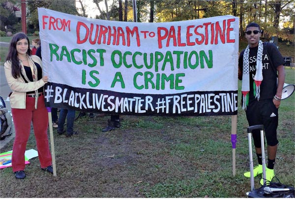 Foto van twee mensen met spandoek: From Durham to Palestine reacist occupation is a crime.