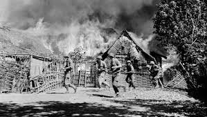 Foto militairen voor brandend dorp