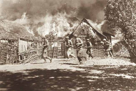 Foto Soldaten trekken door brandend dorp
