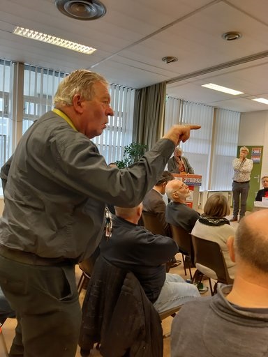 Foto man die spreekt tvanuit zaal tijdens bijeenkomst