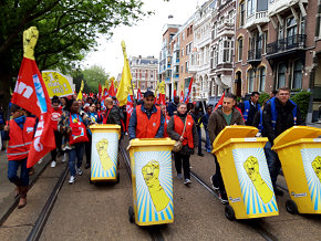 Demonstrerende schoonmakers met gele afvalcontainers