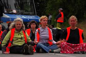 Vrouwen in kleermakerszit op de weg, politiewagen op de achtergrond