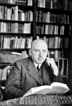 Zwart wit foto Wolf aan tafel met boek en wandvullende boekenkast op achtergrond