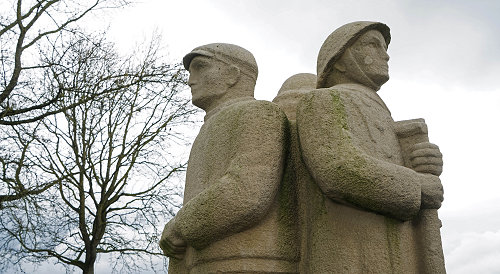 Standbeel drie personen rug tegen rug, kale boom tegen bewolkte heml als achtergrond