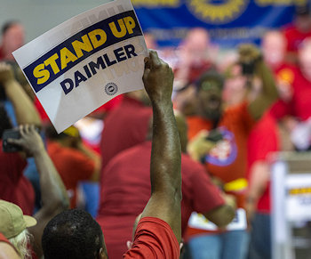 Demo rood geklede werkers met bord Stand Up Daimler