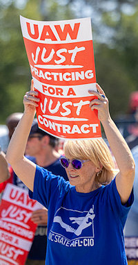 Vrouw met bord UAW Just Praticing for Just Contract