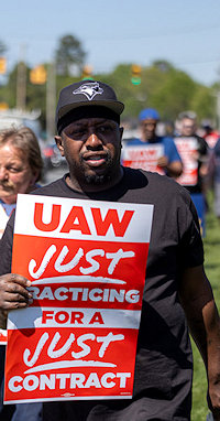 Man met bord UAW Just Practicing for a Just Contract