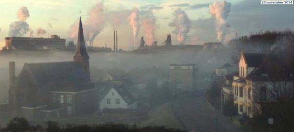 Huizen in mist, op achtergrond (rook/stoom)wolken hoogoverns