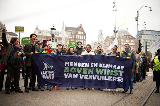 Foto spandoek ' Mensen en klimaat boven winst van vervuilers' op de Dam