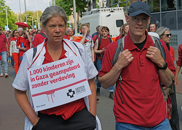 Demonstranden in het rood, spandoek Minister Veldkamp Stop met wegkijken!